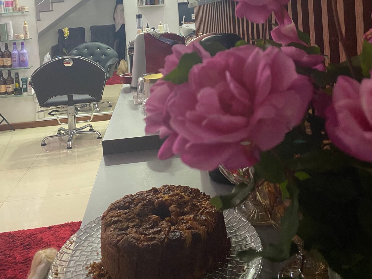 Detalhe do salão com arranjo de flores rosas sobre a mesa de atendimento