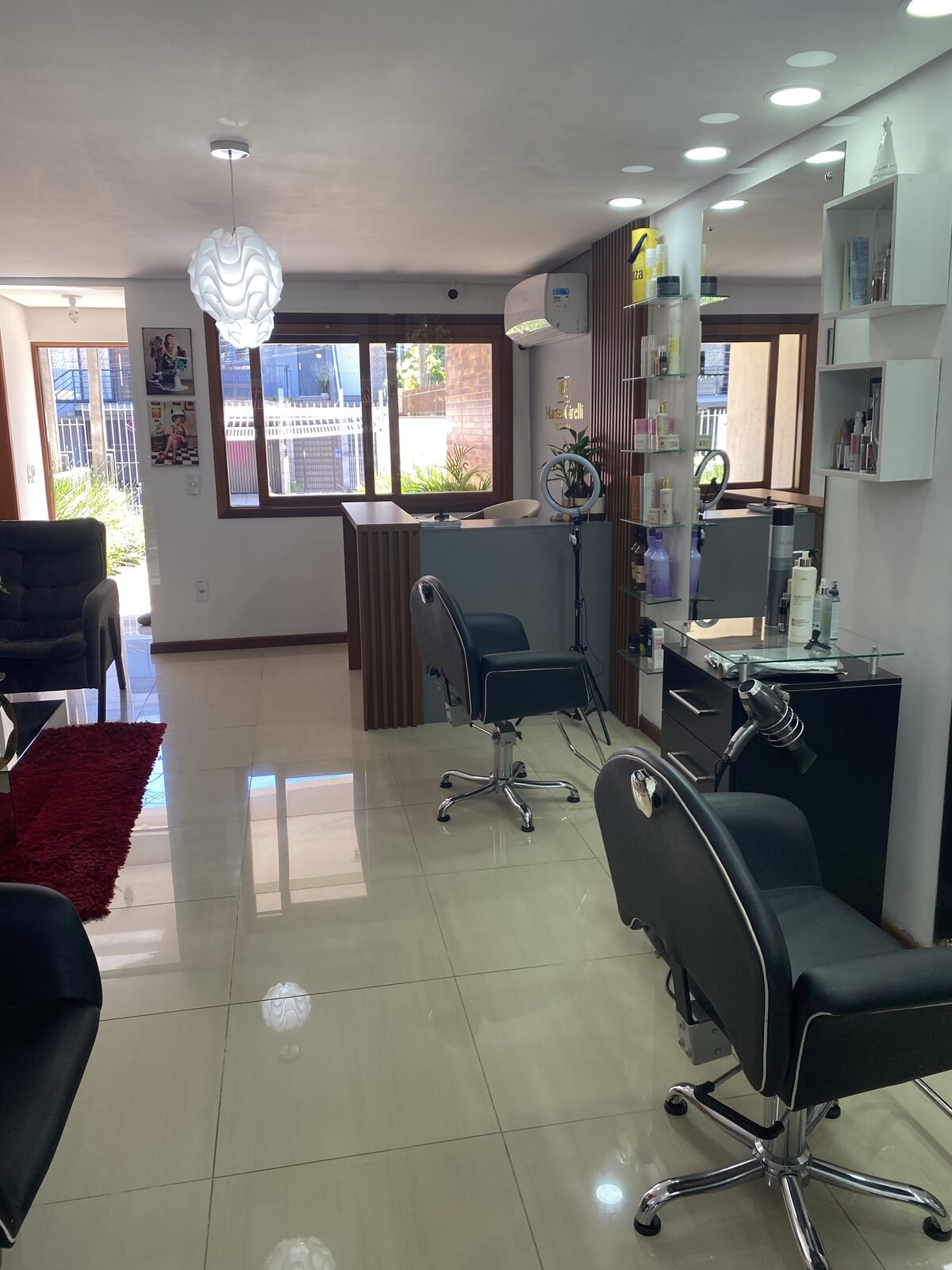 Interior do salão Estética Marisa Girelli, no Residencial Verdes Campos, em Porto Alegre, com cadeiras de atendimento e estantes de produtos